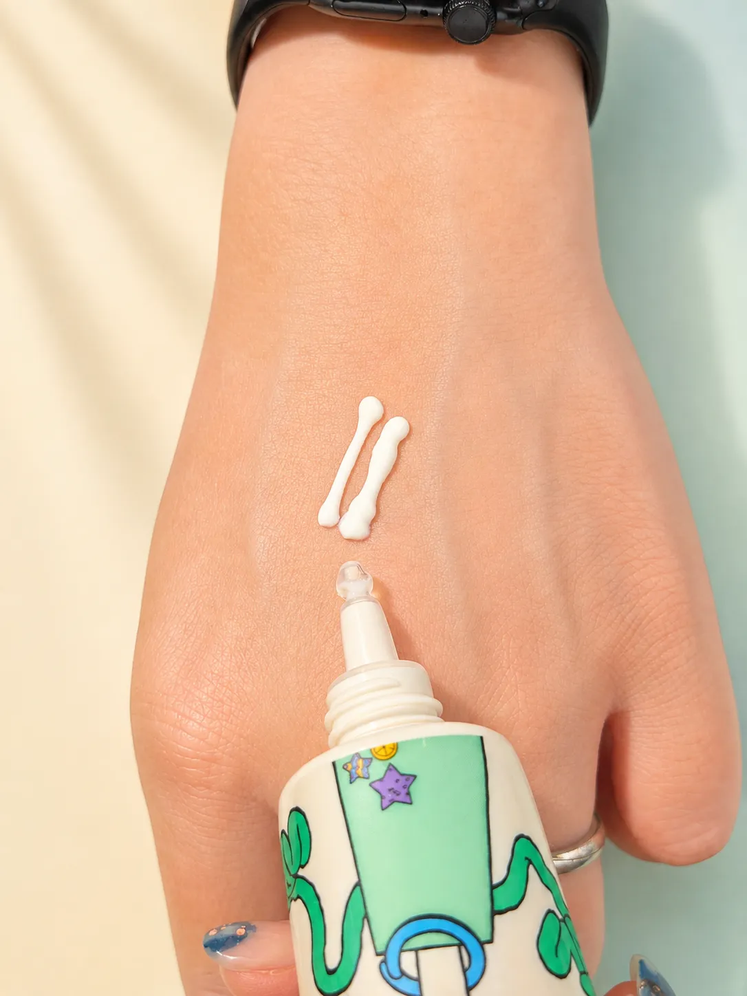 Two lines of the sun serum freshly dispensed onto the back of a hand, next to the tube
